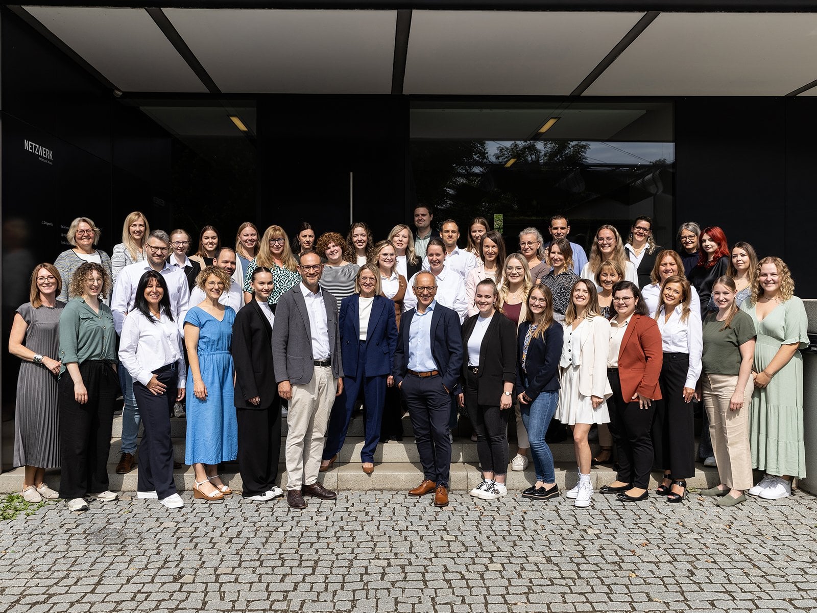 Gruppenfoto des gesamten Teams vor dem Firmengebäude